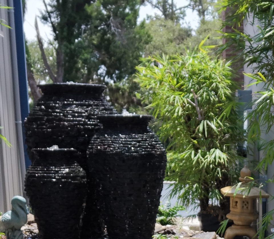Close-up of three black stacked-slate urn fountains with water spilling over the rims