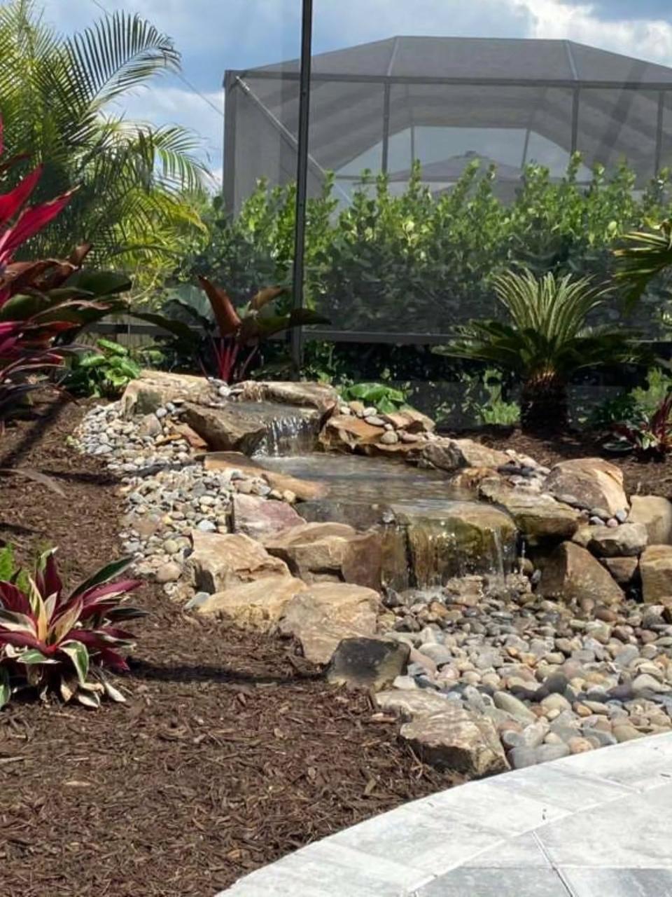 Garden stream with a small waterfall and lush plantings