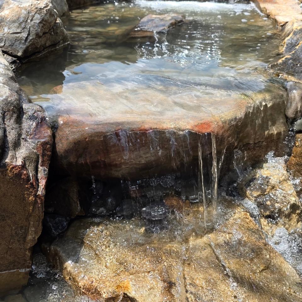 Clear water spilling over a flat stone ledge into a rock stream