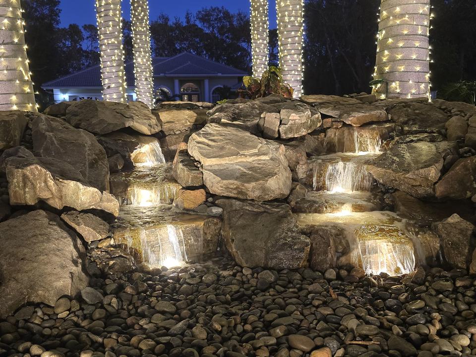 Rock waterfall lit at night with warm underwater lights