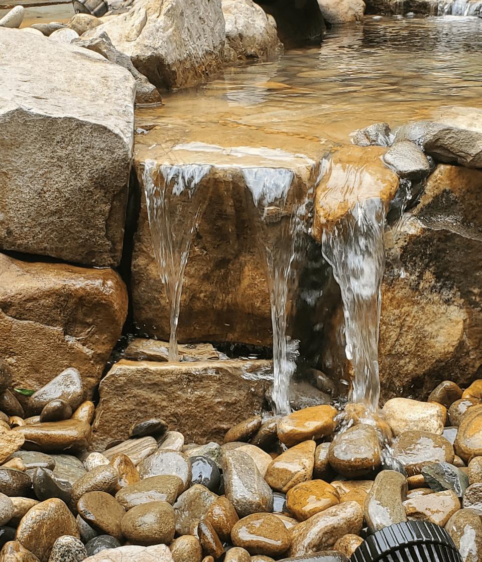 Close-up of clear water sheeting over a flat stone spillway into a rock basin