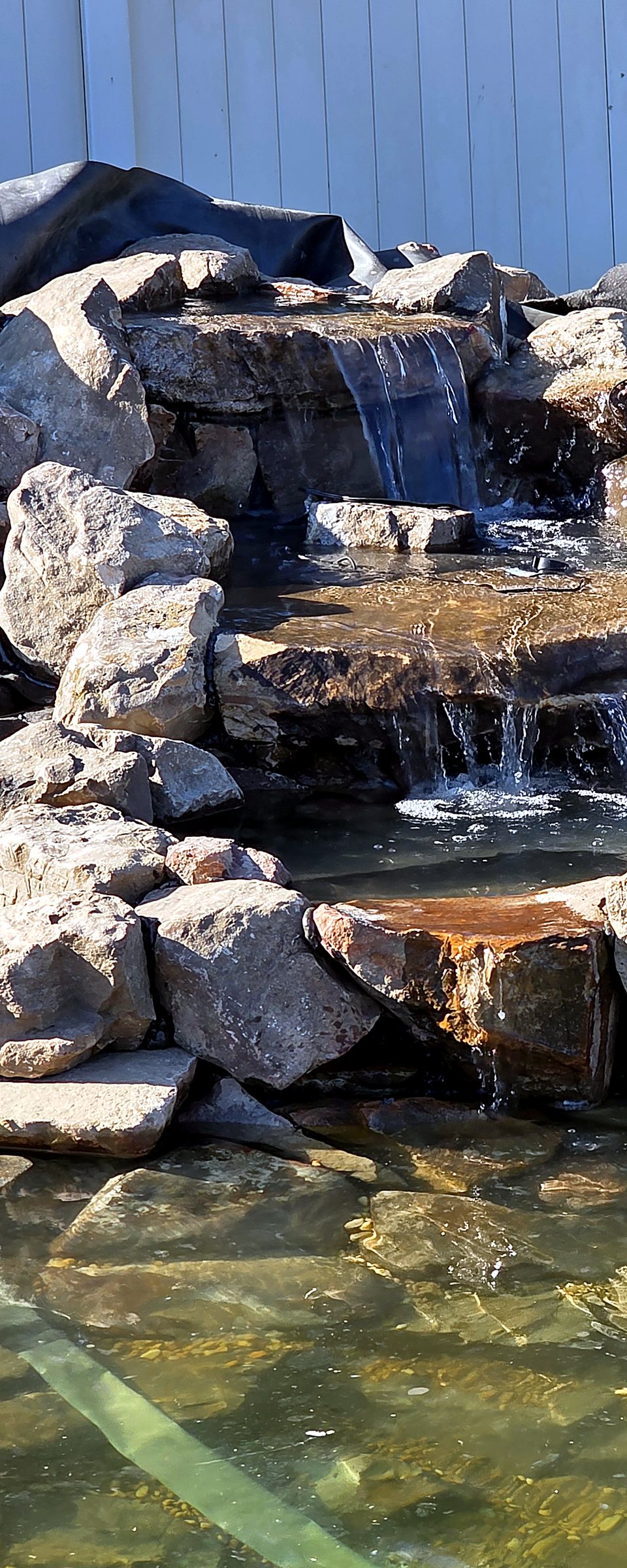 Close-up of the tiered stone waterfall spilling into the swimming pond