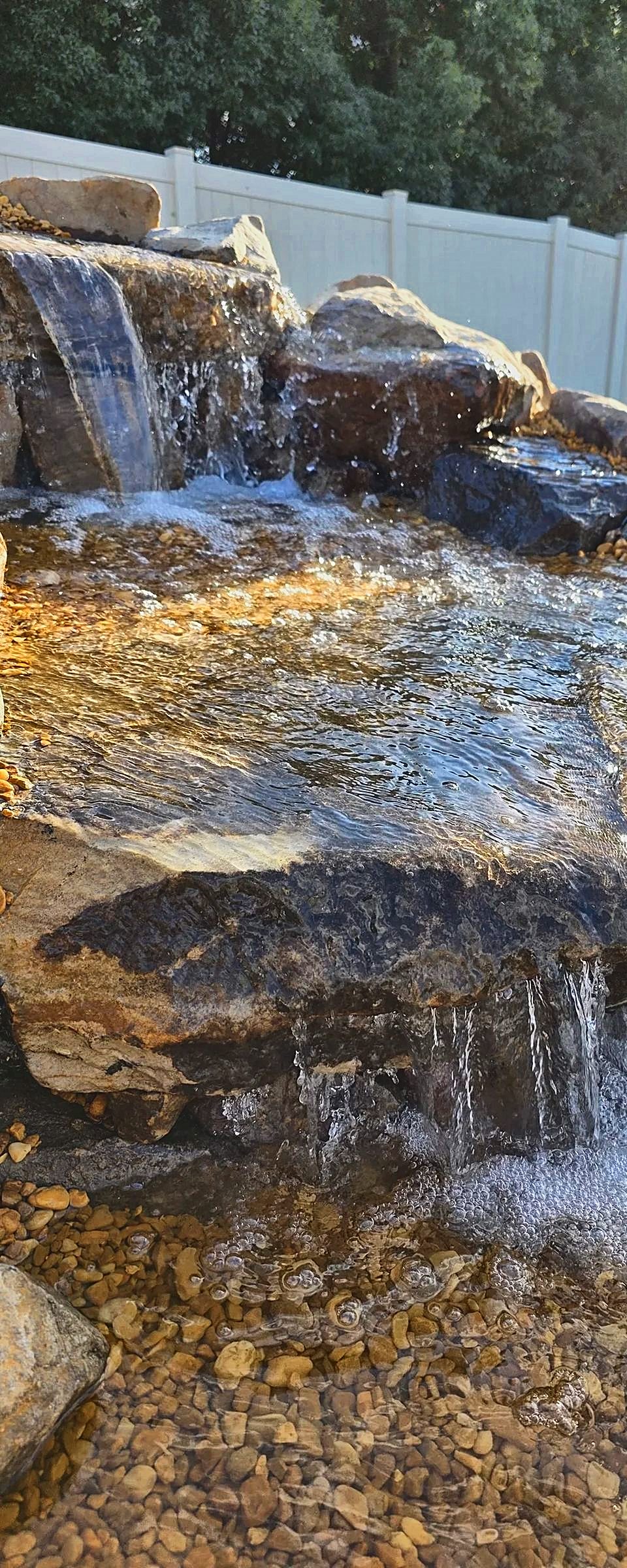 Close-up of the stone waterfall spilling over a flat ledge into the swimming pond