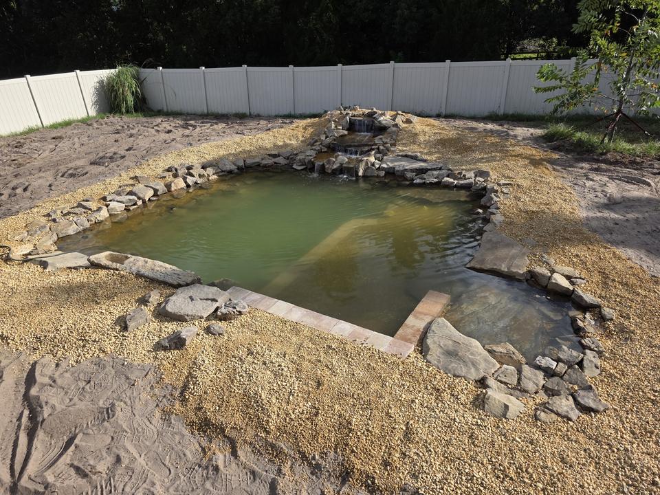 Recreational swim pond with multi-tier rock waterfall and gravel beach